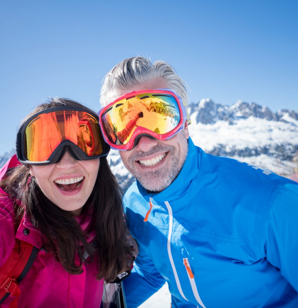 Adult couple taking a selfie while skiing looking very happy