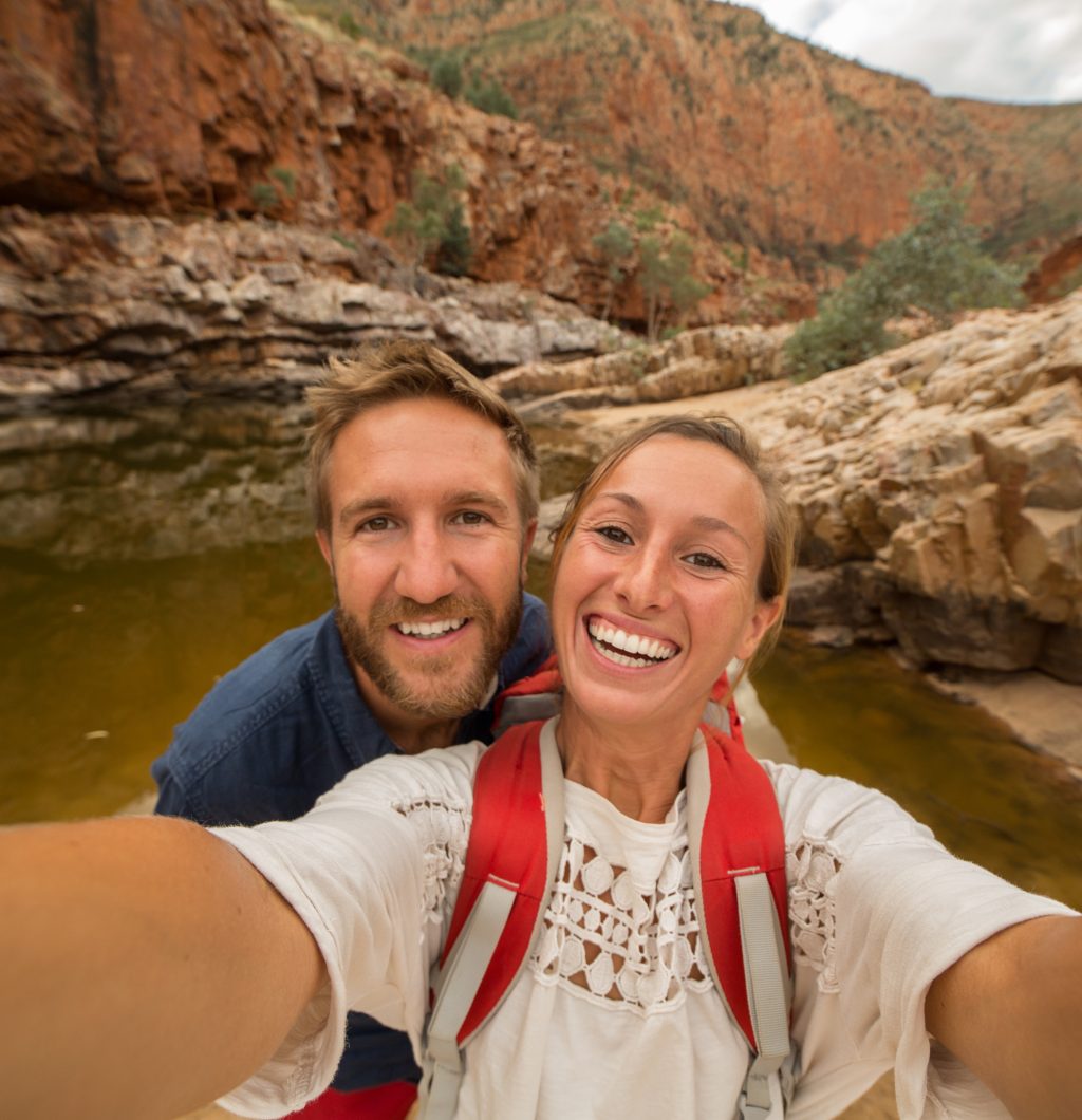 Caucasian couple traveling take a selfie portrait in the Australia's outback while hiking one of the trails in the West McDonnell national park in the Northern Territory.